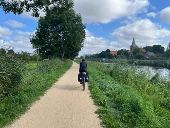 Eine Radfahrerin mit Gepäcktaschen auf dem Radfernweg Alte Salzstraße bei Berkenthin.