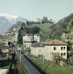 Bellinzona: hinten die Montebello-Burg, vorne der Personenzug | Bellinzone: à l’arrière-plan, le château de Montebello; au premier, le train de voyageurs | Bellinzona: dietro il Castello di Montebello, davanti il treno passeggeri, ≈ 1975.