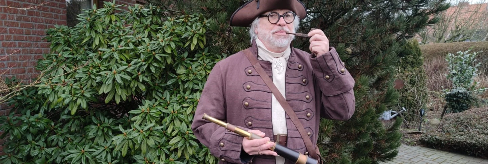 Hafenmeister Quirinus Hafenmeister in historischer Kleidung mit Dreispitz, Pfeife und Fernrohr im Freien