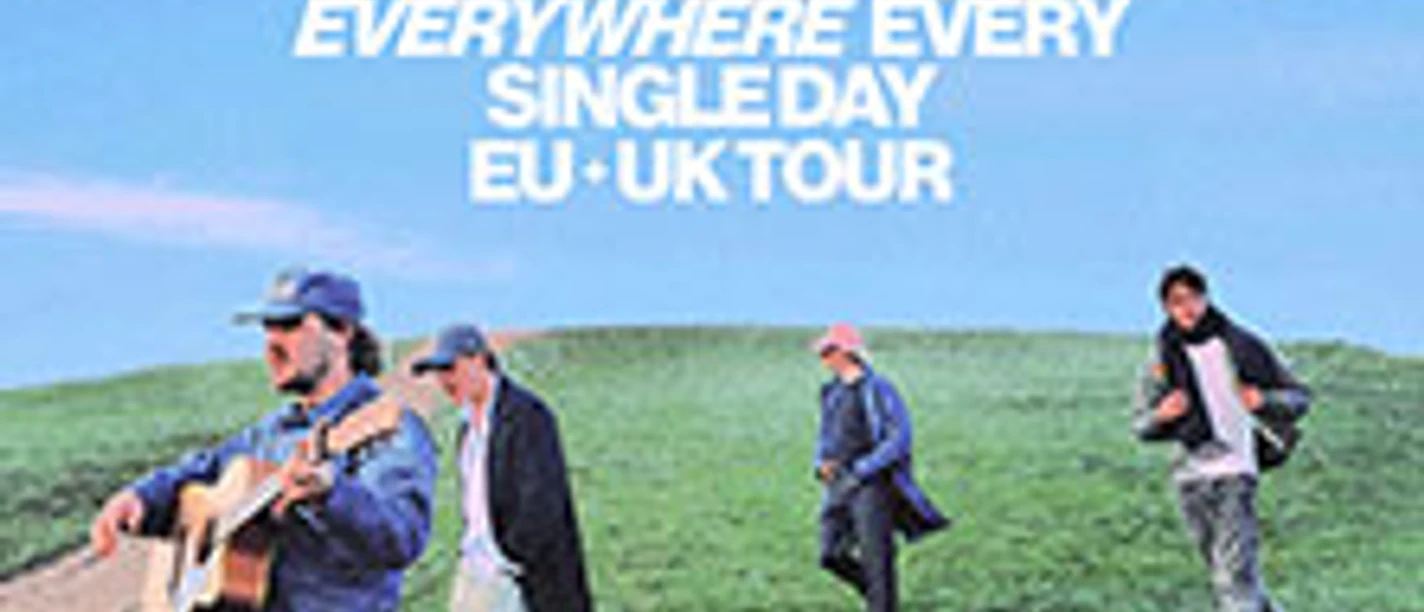 Vier Musiker gehen über eine Wiese, einer spielt Gitarre, darüber Tourdaten-Schriftzug.