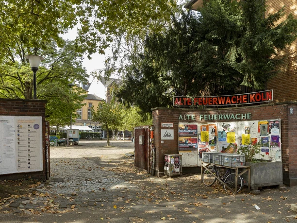 Alte Feuerwache Entrance to the Old Fire Station Cologne with billboard, trees and paved courtyard area.