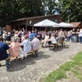 Boßelfest.jpg Besucher sitzen bei sonnigem Wetter an Tischen im Freien.