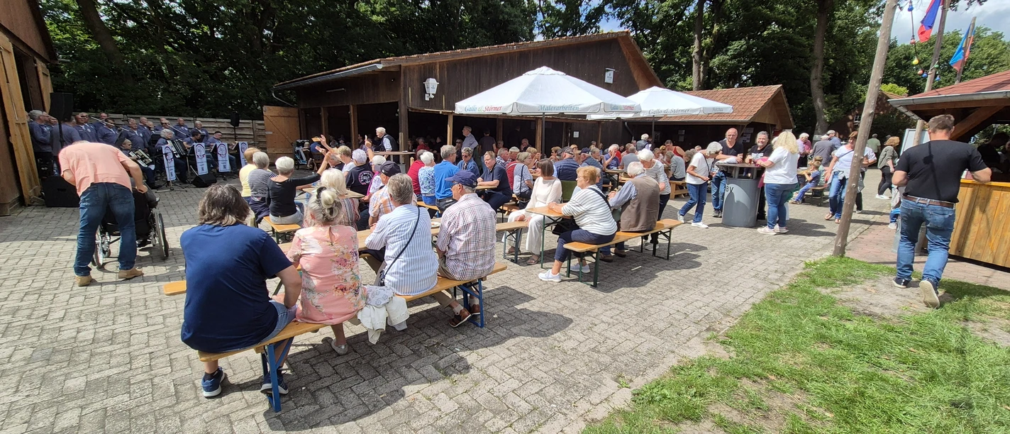 Boßelfest.jpg Besucher sitzen bei sonnigem Wetter an Tischen im Freien.