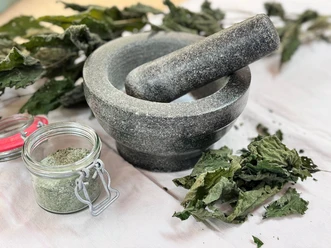 Kräutersalz_Mörser_quer2_MK.jpg Steinmörser mit Stößel, getrockneten Kräutern und einem Glas selbst gemahlenem Kräutersalz.