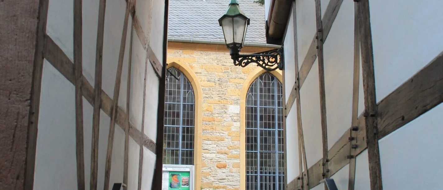 Fachwerkpatt Schmale Gasse zwischen Fachwerkhäusern mit Blick auf Kirchenfenster und Laterne