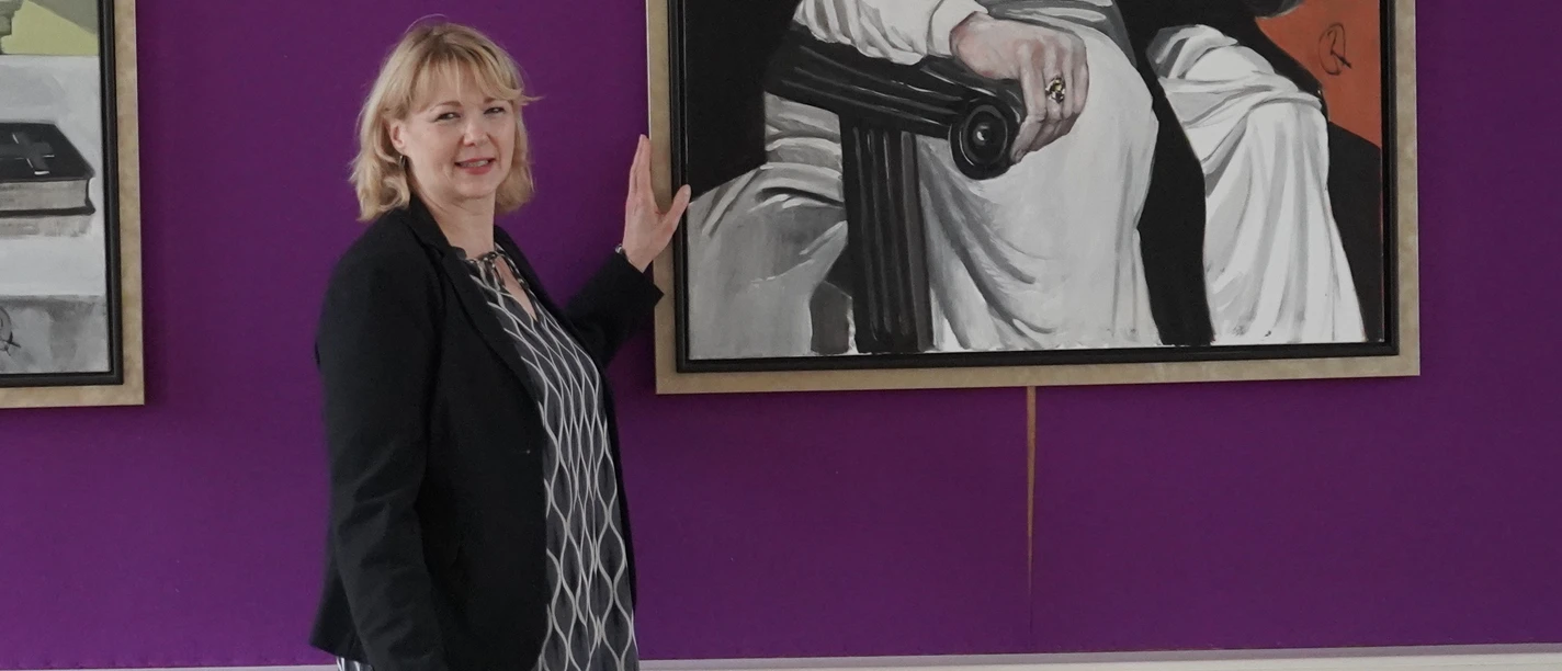 Marienfeld-Bärbel-Tophinke-mit Bildergalerie-der-Äbte-Teutoburger-Wald-Stadt-Harsewinkel-U.-Mussmann.jpg Die Gästeführerin Bärbel Tophinke steht vor der Bildergalerie der Äbte.