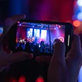 Stadthalle Bremerhaven_HAI_DANG_DUONG_00271.jpg Aufnahme eines Smartphones, das eine Konzertbühne mit bunter Beleuchtung filmt.