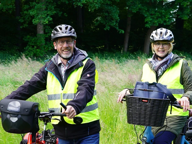 Marienfeld-Bärbel-und-Werner-Tophinke-mit-Rädern-Teutoburger-Wald-Stadt-Harsewinkel-Tophinke.jpg Werner und Bärbel Tophinke mit Warnweste und Helm und die Lenker ihres Fahrrades in der Hand.