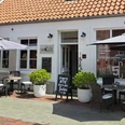 hafen5.png Weißes Café Hafen 5 mit rotem Ziegeldach. Davor stehen Tische, Stühle und Schirme.