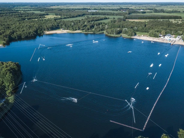 DJI_0089_Blue Bay Spadener See_Hergen Hanke.jpg Luftaufnahme der Wakeboardanlage Blue Bay am blauen Spadener See, umgeben von grünen Wäldern.