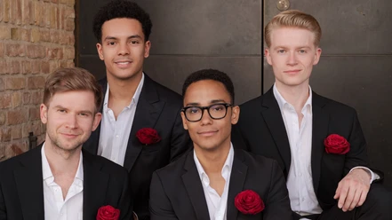 Vier Sänger der German Gents in schwarzen Anzügen mit roten Rosen am Revers.