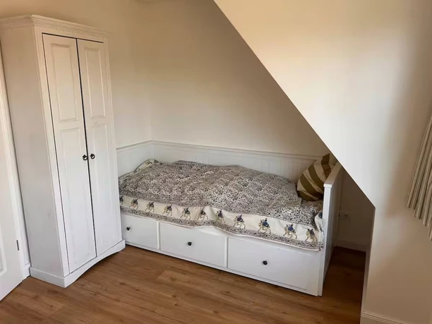kinderzimmer-nische-dachschraege-weiss Ein weißes Funktionsbett in einer gemütlichen Dachnische neben einem passenden Kleiderschrank.