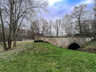 Brücke Hasselbachtal 2.jpg Historische Steinbogenbrücke im Hasselbachtal, umgeben von Bäumen und Rasenflächen.