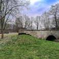 Brücke Hasselbachtal 2.jpg Historische Steinbogenbrücke im Hasselbachtal, umgeben von Bäumen und Rasenflächen.