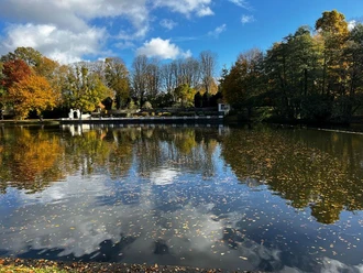Auf den Spuren von Wassermann, Pau und Kaiser-Friedrich-Park 2 (c) Ökologie-Zentrum Aachen e.V..jpg Umgeben von herbstlichen Bäumen spiegelt sich der blaue Himmel auf der Wasseroberfläche eines Sees.