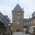 Die Altstadt von Monheim mit interessanten Geschichten von damals und heute Der Schelmenturm in Monheim am Rhein, ein historischer Backsteinturm mit Spitzdach und Torbogen, umgeben von Altstadthäusern.