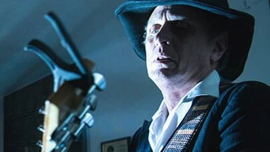 Makkela Musiker mit Hut und Gitarre bei einem Folk-Konzert im Scheinwerferlicht