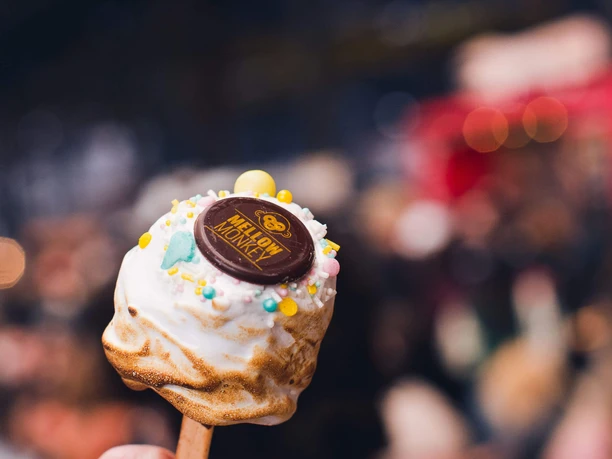 Street Food Festival in Ehrenfeld Süßer Marshmallow am Stiel mit Deko vor unscharfem Festivalhintergrund