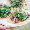 Street Food Festival in Ehrenfeld Three freshly filled tacos with meat, herbs, onions and lime on a plate.