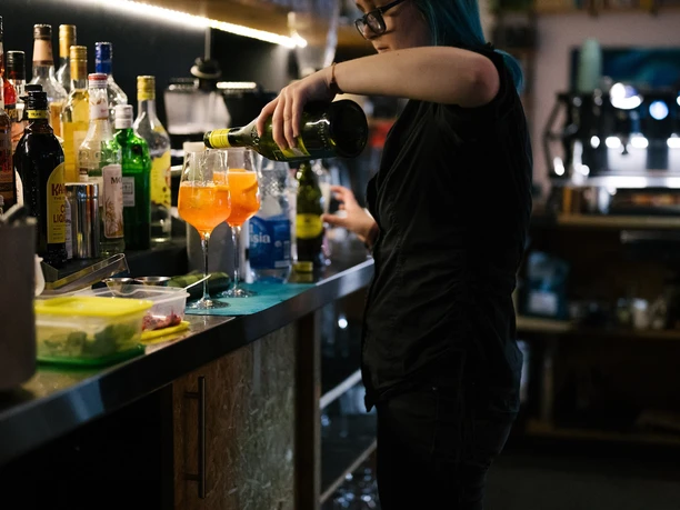 RheinMain Hanau AJOKI - Bar Person bereitet Getränk an einer beleuchteten Bar zu