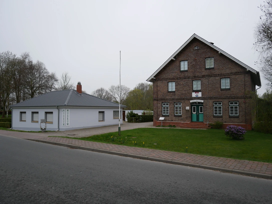 Heimatmuseum Geversdorf Historisches Backsteingebäude neben flachem Anbau des Heimatmuseums Geversdorf an einer Straße.