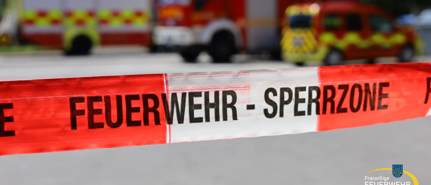 Durchs Feuer gehen - Brandschutztour mit der Feuerwehr Mettmann Absperrband "Feuerwehr - Sperrzone" vor unscharfen Einsatzfahrzeugen der Feuerwehr Mettmann.