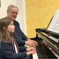 Pro Musica Mädchen spielt Klavier, Lehrer unterstützt beim Schnupperunterricht in der Musikschule