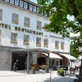 Weißes Gebäude des Hotels Ratskeller mit Außengastronomie unter Bäumen.