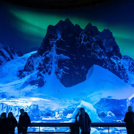 View of the ANTARCTICA exhibition at Panometer Leipzig | Leipzig Convention Bureau People viewing the panorama of the ANTARCTICA exhibition in a dimly lit interior – presented by Leipzig Convention Bureau