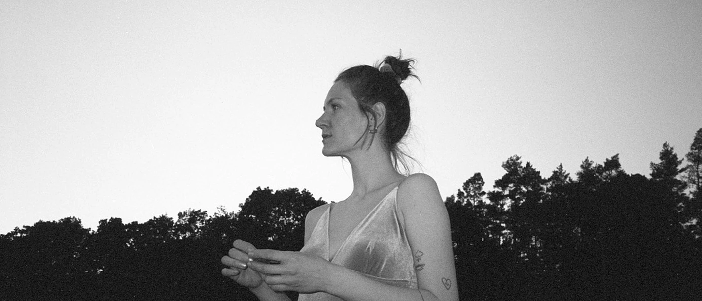 SEASOUL in Büsum Ein Schwarzweißbild von einer jungen Frau, die ein Top trägt und in die Ferne schaut. Im Hintergrund ist ein Wald.