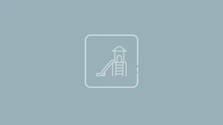 KVWN_25_Icons_POIs_Spielplatz.jpg Weißes Icon einer Spielplatz-Rutsche mit Turm auf blau-grauem Hintergrund.