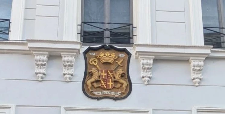Die mächtigen Frauen von Burtscheid (c) Ökologie-Zentrum Aachen.jpg Helle Hausfassade mit einem historischen Wappen, das unterhalb eines Fensters angebracht ist.