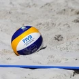 Ein Beachvolleyball liegt im Sand neben der Feld-Linie.
