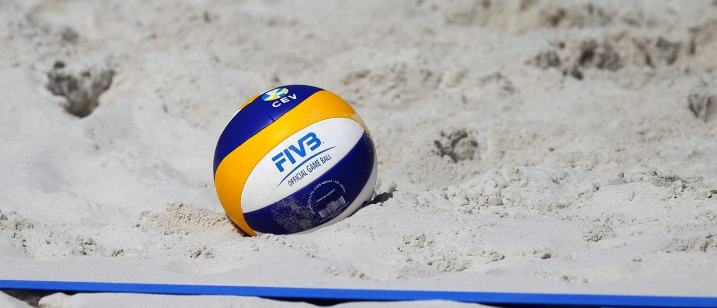 Beachvolleyball (c) Pixabay.jpg Ein Beachvolleyball liegt im Sand neben der Feld-Linie.