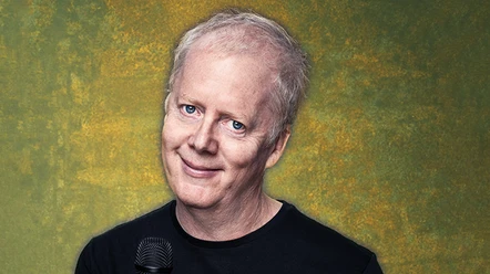John Doyle Man with microphone in front of yellow-green background with a slight smile