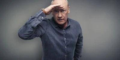 Person in blue shirt holds hand protectively over eyes, greets or looks challengingly.