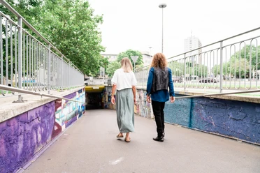 Zwei Personen laufen in eine Unterführung dessen Wände mit Street Art dekoriert sind.