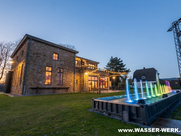 Wassershow am Wasserwerk Tecklenburg.jpg Beleuchtete Wassershow vor altem Wasserwerk in Tecklenburg bei Abenddämmerung