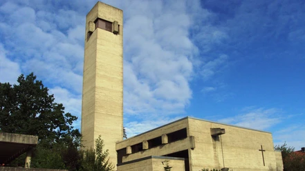 Betonfassade der Martin-Luther-Kirche mit markantem Turm unter blauem Himmel.