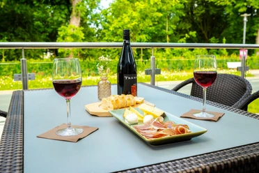 Außenterrasse im Hotel am Park Außenterrasse mit Tisch, Rotwein, Antipasti und Blick ins Grüne.