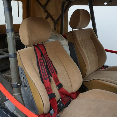 Automuseum - Rallye-Wagen - Innen.JPG Innenraum eines historischen Rallye-Geländewagens mit braunen Sportsitzen und roten Renngurten, aufgenommen in einer Ausstellung.