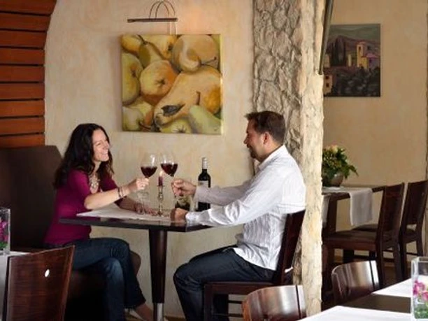 Ein Paar Paar stößt mit Rotwein an einem Tisch im Restaurant an.