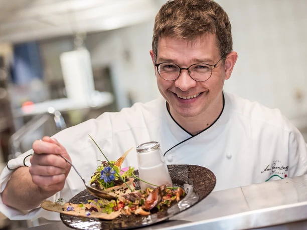 Frische, leichte und kreative Küche am Rosenberg Koch richtet kreativ angerichtetes Gourmetgericht mit frischen Kräutern an.