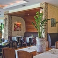 Hotel-Restaurant Am Rosenberg Restaurantbereich mit Holztischen, gepolsterten Bänken und Pflanzen im Innenraum.