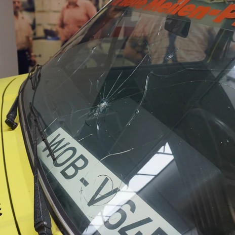 Automuseum - Scheibe.JPG Beschädigte Windschutzscheibe eines gelben Oldtimers im Museum.