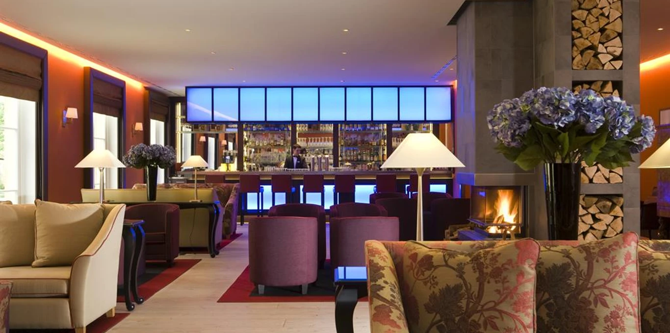 Oscar´s Bar im Gräflichen Park Barbereich mit Sesseln, Kamin und blau beleuchtetem Tresen im Gräflichen Park.