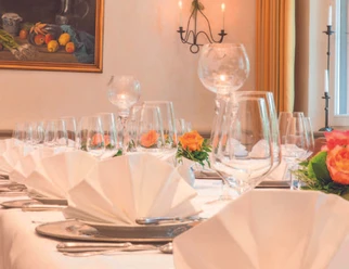 Gedeckter Tisch - Der Schwallenhof Festlich gedeckter Tisch mit weißen Servietten, Weingläsern und Rosen.