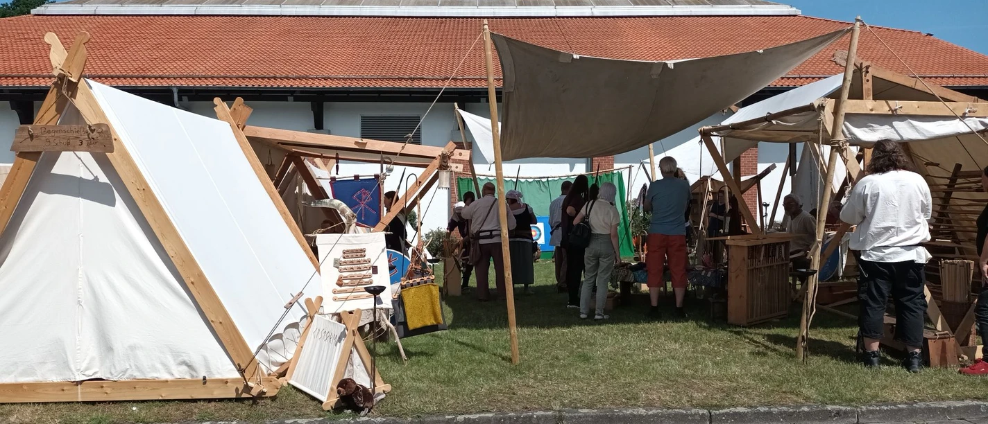 2023_Mittelaltermarkt Gebhardshagen (3)_HD_16zu9.jpg Weiße Leinen-Zelte und Besucher auf dem Mittelaltermarkt an der Wasserburg Gebhardshagen.