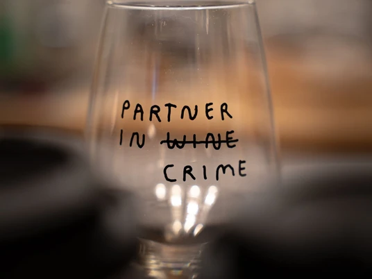Wein & Crime Weinglas mit Aufschrift "Partner in Wine Crime", wobei "Wine" durchgestrichen ist.