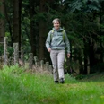 Kerstin Rubel Kerstin Rubel wandert lächelnd mit Rucksack auf einem grünen Waldweg in Wipperfürth.